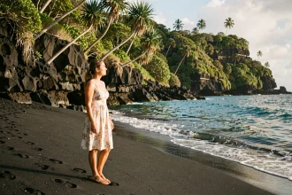 Femme découvrant la plage de sable noir de Grande Anse à La Réunion lors de son premier voyage sur l'île