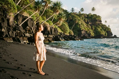 Femme découvrant la plage de sable noir de Grande Anse à La Réunion lors de son premier voyage sur l'île